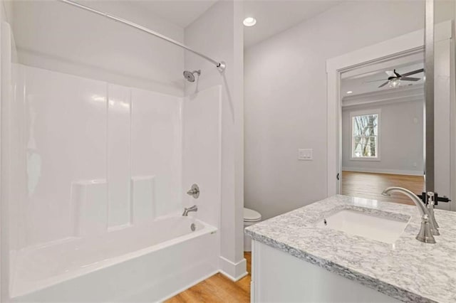 bathroom with toilet, ceiling fan, wood finished floors, tub / shower combination, and vanity