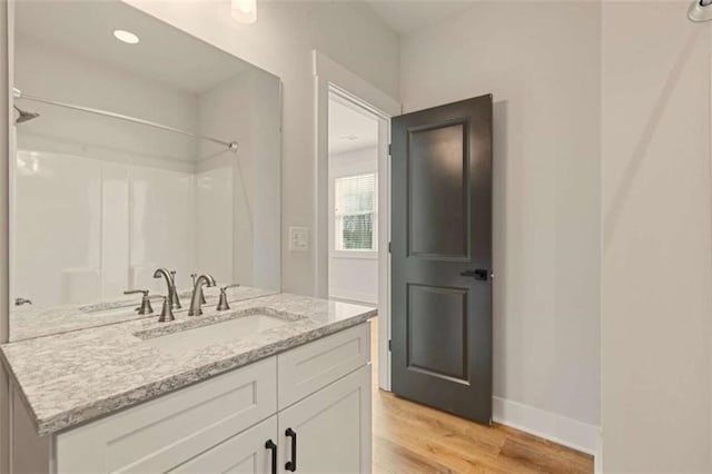 full bath with baseboards, wood finished floors, walk in shower, vanity, and recessed lighting