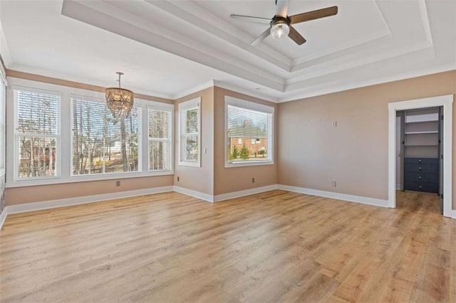 interior space featuring ceiling fan with notable chandelier, a raised ceiling, light wood-style flooring, and baseboards