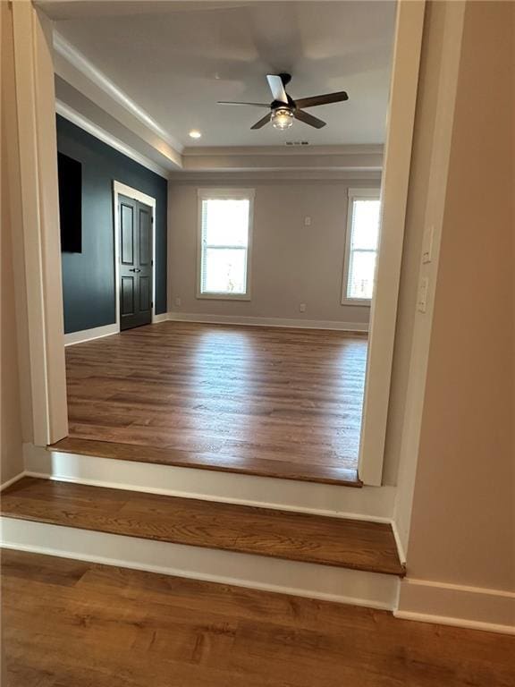 spare room with ceiling fan, plenty of natural light, baseboards, and wood finished floors