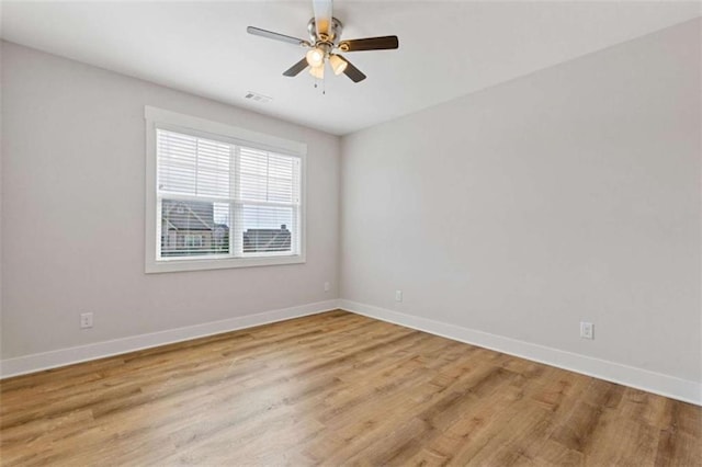 spare room featuring a ceiling fan, light wood-type flooring, and baseboards