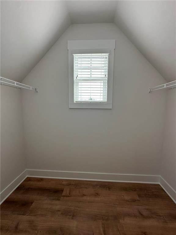 additional living space featuring lofted ceiling, dark wood-style flooring, and baseboards