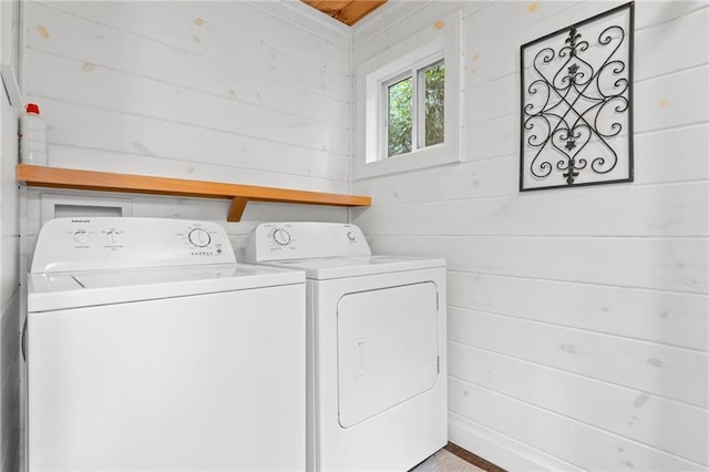 clothes washing area featuring washing machine and clothes dryer and wooden walls