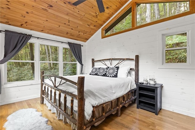 bedroom with wood walls, lofted ceiling, light wood-type flooring, ceiling fan, and wooden ceiling