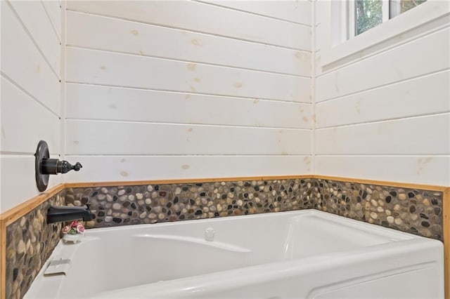 bathroom with a washtub and wood walls