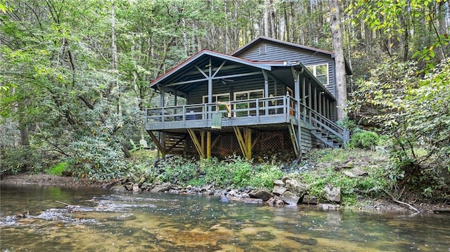 view of front of home with ceiling fan and a deck with water view