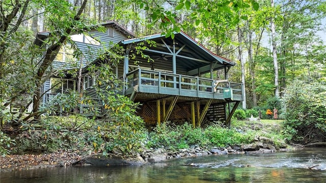 rear view of property with ceiling fan and a deck with water view