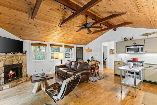 living room with lofted ceiling with beams, light hardwood / wood-style flooring, wood ceiling, ceiling fan, and a stone fireplace