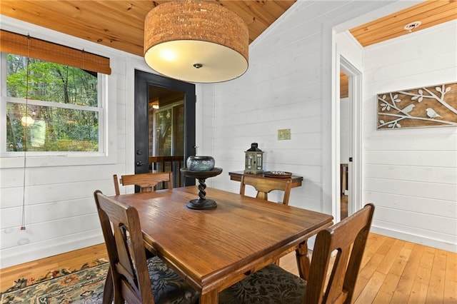 dining room featuring wooden walls, wooden ceiling, vaulted ceiling, and wood-type flooring