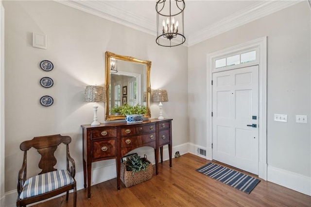 entrance foyer featuring baseboards, crown molding, visible vents, and wood finished floors