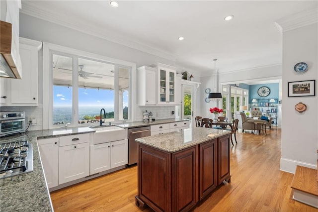 kitchen with decorative backsplash, appliances with stainless steel finishes, crown molding, light wood-style floors, and a sink