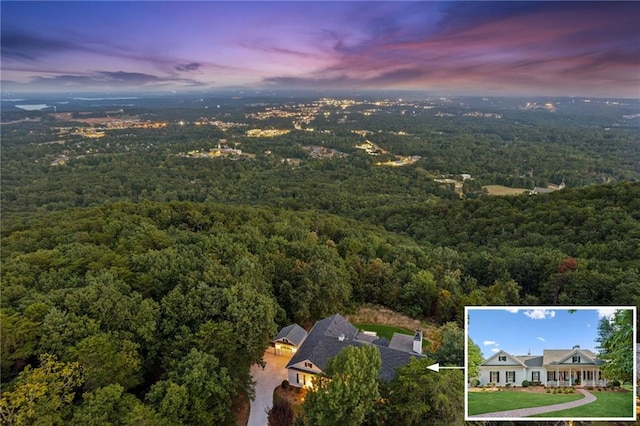 aerial view at dusk featuring a forest view