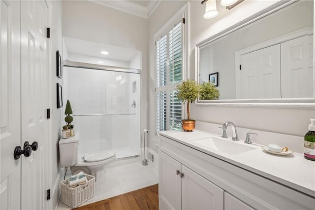 bathroom with toilet, wood finished floors, crown molding, vanity, and a shower stall