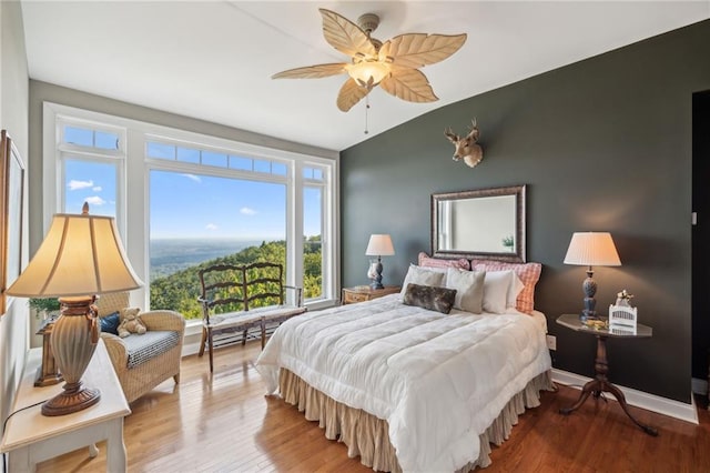 bedroom featuring a ceiling fan, baseboards, vaulted ceiling, and wood finished floors