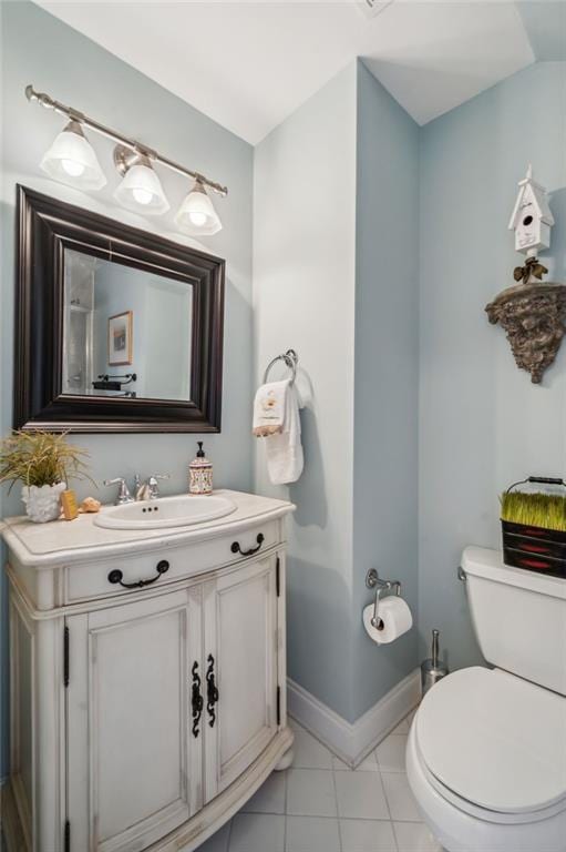 half bathroom with tile patterned flooring, vanity, toilet, and baseboards