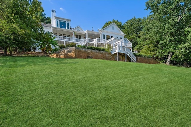 rear view of property featuring stairway and a yard