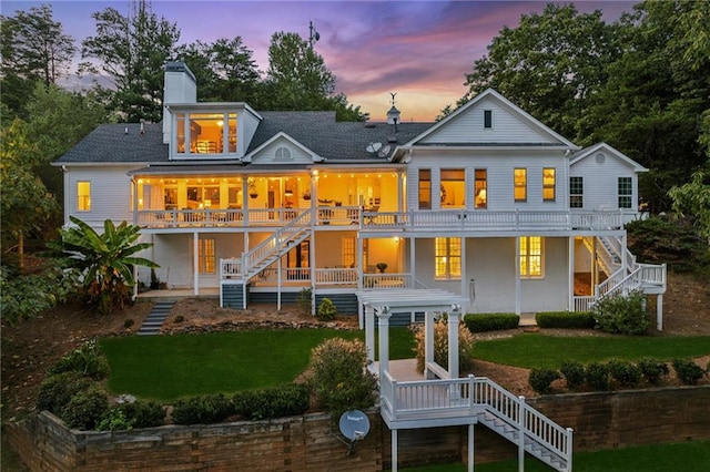 back of property at dusk with a chimney, a yard, and stairway