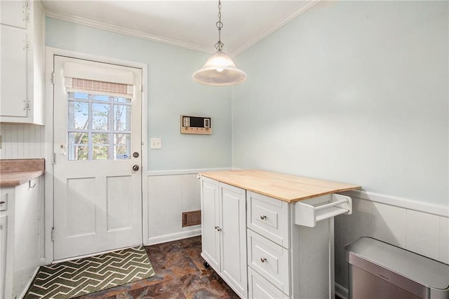 doorway featuring wainscoting, visible vents, and crown molding