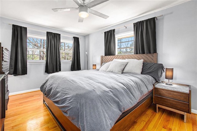 bedroom with light wood-style floors, multiple windows, and baseboards