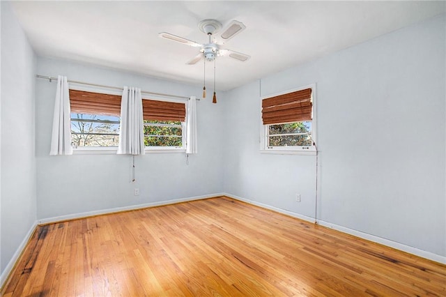 spare room with baseboards, light wood-style floors, a ceiling fan, and a healthy amount of sunlight