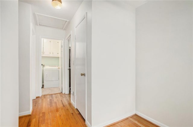 hallway with washer / dryer, attic access, baseboards, and light wood-style flooring