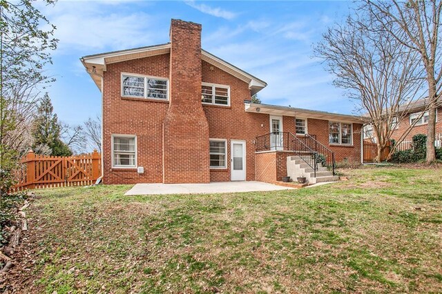 rear view of house with brick siding, a chimney, a patio area, and a fenced backyard