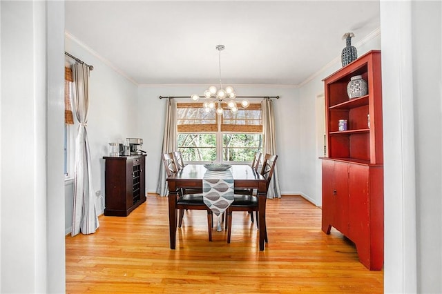 dining room featuring light wood-style floors, ornamental molding, and a notable chandelier