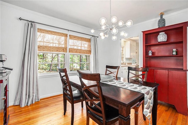 dining space with light wood-style floors, baseboards, crown molding, and an inviting chandelier