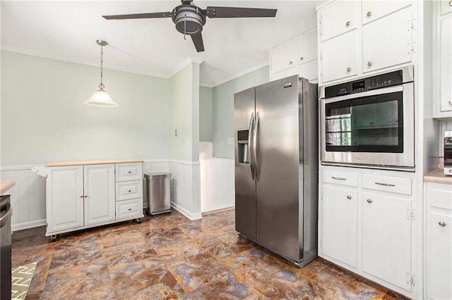 kitchen with a wainscoted wall, stainless steel appliances, white cabinetry, and pendant lighting