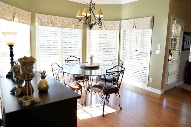 dining area with baseboards, an inviting chandelier, wood finished floors, and crown molding