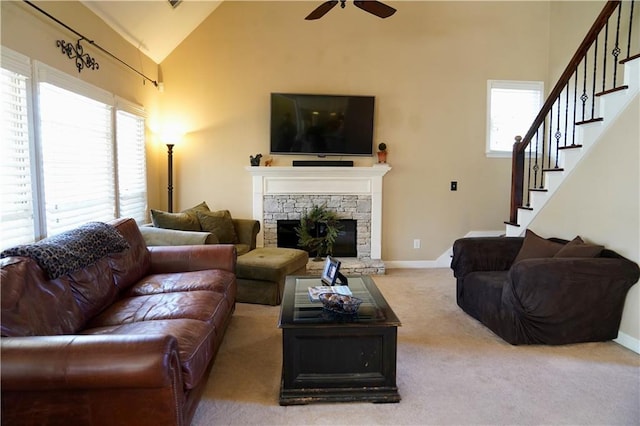 carpeted living area featuring a stone fireplace, stairway, high vaulted ceiling, and baseboards