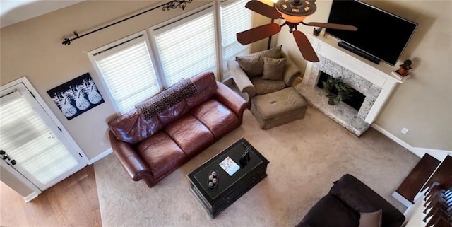 living room featuring a fireplace, a ceiling fan, carpet, and baseboards