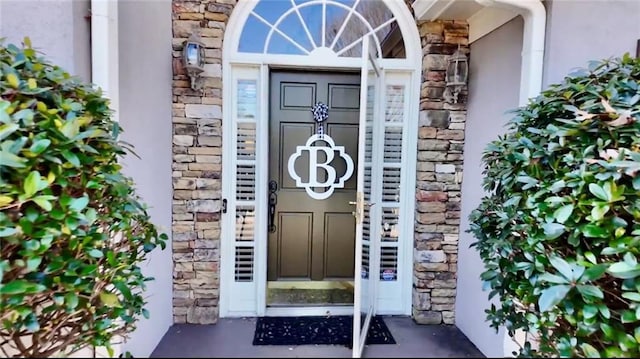 doorway to property featuring stucco siding and stone siding