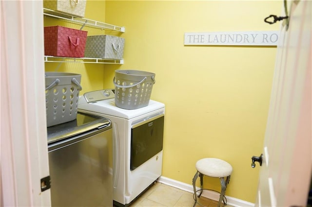 laundry area with tile patterned floors, baseboards, washing machine and dryer, and laundry area