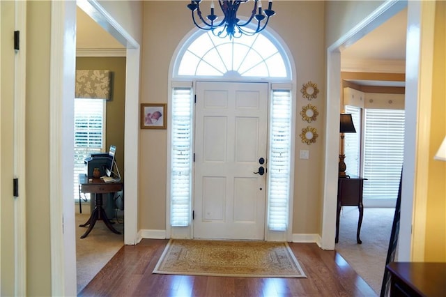 entryway with a notable chandelier, baseboards, dark wood-style flooring, and ornamental molding