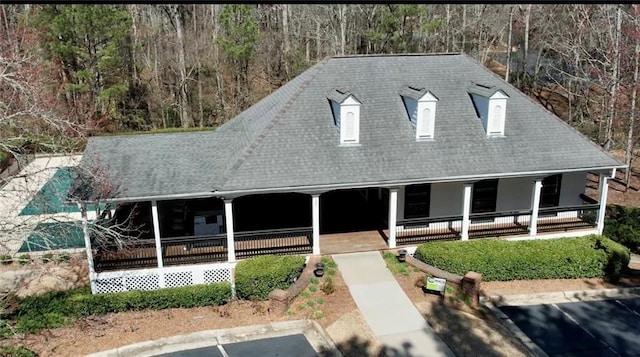 farmhouse inspired home with covered porch and a shingled roof