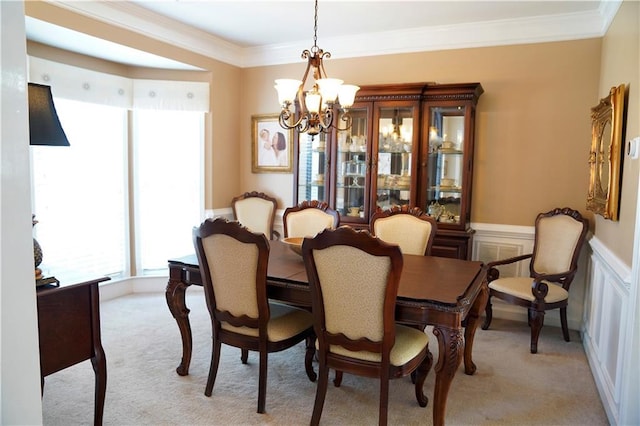 dining room with a wainscoted wall, ornamental molding, a decorative wall, light colored carpet, and a chandelier