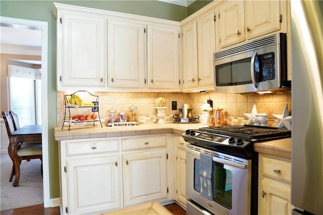 kitchen with decorative backsplash, tile countertops, and appliances with stainless steel finishes