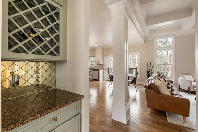 2660 Burnt Hickory Dr, Cumming, GA 30028 - bar area with decorative columns, stainless steel dishwasher, crown molding, decorative backsplash, and dark wood-style flooring