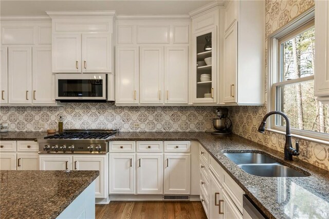 2660 Burnt Hickory Dr, Cumming, GA 30028 - kitchen with a sink, dark stone counters, stainless steel gas stovetop, white cabinets, and glass insert cabinets