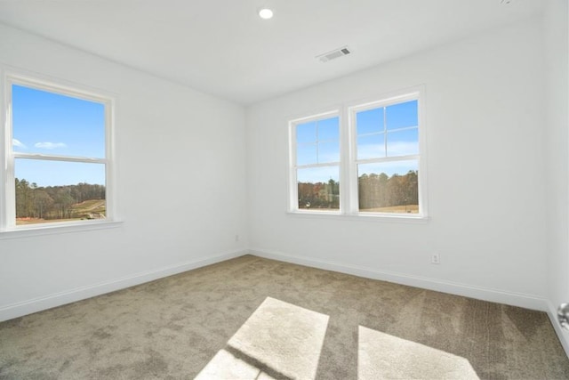 spare room with light colored carpet, visible vents, and plenty of natural light