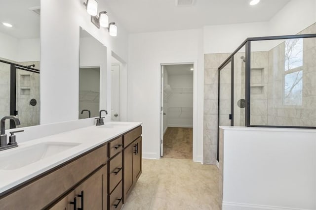 full bath featuring double vanity, a sink, a walk in closet, and a shower stall