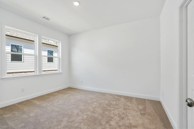 spare room with visible vents, light carpet, and baseboards