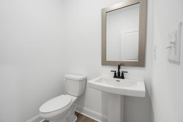 bathroom featuring a sink, wood finished floors, toilet, and baseboards