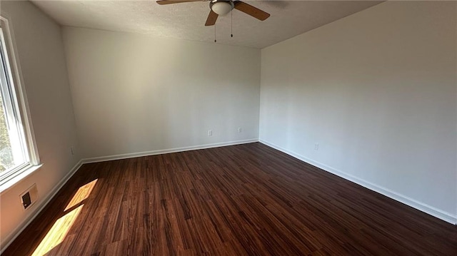 unfurnished room with a textured ceiling, a ceiling fan, dark wood-type flooring, and baseboards