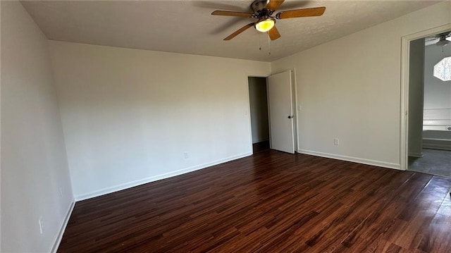 spare room featuring a textured ceiling, baseboards, dark wood-type flooring, and a ceiling fan