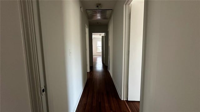 corridor with attic access, dark wood-type flooring, and baseboards