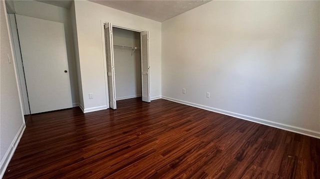 unfurnished bedroom featuring baseboards, dark wood-style flooring, and a closet