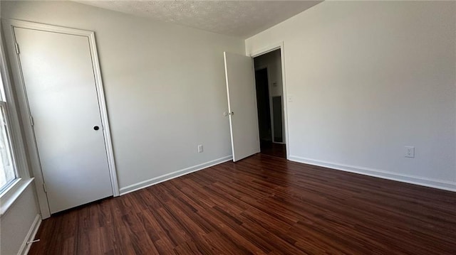 unfurnished room featuring baseboards, a textured ceiling, and wood finished floors