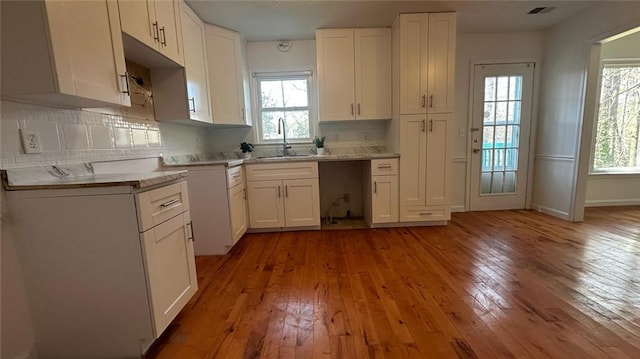 kitchen with hardwood / wood-style floors, plenty of natural light, tasteful backsplash, and a sink